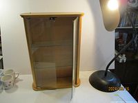 Front view of the wood-framed glass display case with door open, showing interior glass shelves.