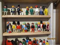 Top two shelves show various vintage Fisher Price People figures and other toy figures in multiple poses and outfits, including adults, children, and specialized figures like soldiers and workers