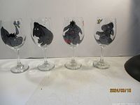 Four clear wine glasses featuring different hand-painted images of Eeyore from Winnie the Pooh.