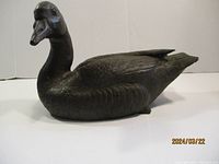 Front side view of the bronze duck sculpture showing detailed texture and form.