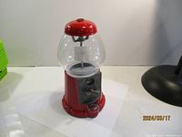 Full view of the red metal gumball machine showing clear globe and base.