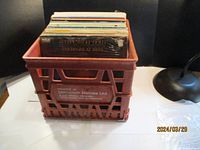 Plastic milk crate filled with many vinyl albums stacked vertically
