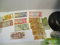 Photo showing various international bills including Canadian 2 dollar note, Ugandan 1000 shillings, and Barbadian notes.