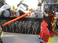 Wide view of Star Wars collection box featuring stormtrooper graphics, Mandalorian helmet, lightsaber, R2-D2 figure, and other items.