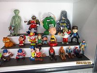 Wide view of entire assortment of toy figures arranged on two levels of shelf, showing various characters in different poses and colors.