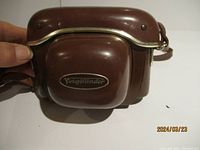 Close-up of the brown leather carrying case featuring Voigtlander branding on the front and metal clasp.