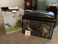 Photo showing the marina 360 aquarium with plastic lid, filter, and decorative rocks inside