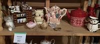 All items displayed on wooden shelving including decorative teapots, ceramic figurines, and trinket boxes