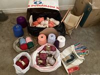 Overhead view of yarn skeins and cones collected in bags and boxes, showing colors and quantity.