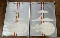 Two original Montreal 1976 Olympic Stadium architecture posters laid flat, showing front side with architectural line drawings and rainbow stripes.