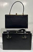 Two black leather handbags, one with a single top handle and the other with dual shoulder straps, both with gold tone detailing on closures.