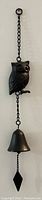 Full view of the entire vintage cast iron owl wind bell hanging vertically, showing owl figure, bell, and pendulum.