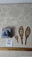 Boxed Arctic Hunt strategy game and three miniature wooden snowshoes displayed on fabric background with ruler for scale.