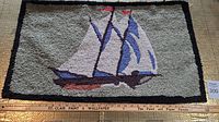 Full view of hooked rug showing Bluenose ship with colors and border detail.