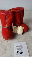 Photo showing pair of red felt Eskimo socks with labels attached, decorated with colorful hand stitching.