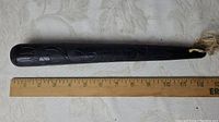 Full-length view of ebony wood billyclub alongside ruler showing 12-inch length
