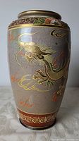 Front view showing the dragon's head and front claws wrapped along the vase body with gold accents.