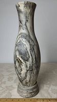 Front angled view of tall grey marble vase with natural swirling patterns.
