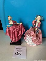 Two Royal Doulton figurines side by side against blue background, showing overall appearance