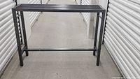 Bar table shown from front on a concrete floor in storage unit.