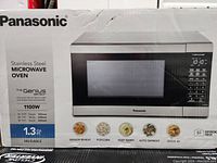 Photo of the Panasonic stainless steel microwave oven box showing model NN-SU65LS and key features like 1100W power, 1.3 cu ft capacity, and sensor cooking options.