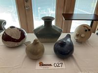 All five items arranged on a table - two birds, two vases, one pig figure visible