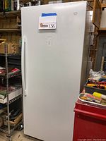 Full front view of white upright freezer in garage setting