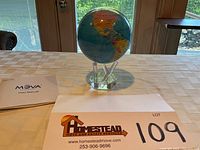 Front view of globe on acrylic stand with user manual and lot sign