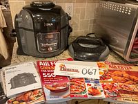 Ninja Foodi cooker with instruction booklets and cookbooks placed beside it on the counter.