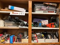 Wide view of two middle shelves showing Porter Cable finish staplers, various boxes of staples and nails, and other hardware items organized in boxes and plastic containers.