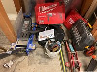 Photo showing the lot contents including PowerTorque 3 Ton floor jack, Milwaukee rotary hammer kit in box, Rockwell SoniCrafter case, Milwaukee inspection scope case, and assorted hand tools in bucket.