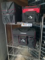Three heavy duty waterproof Husky tool bags on a stainless steel rolling rack, showing the front view of the bags with pockets and the rack