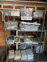 Full view of stainless steel rolling shelving unit with multiple shelves holding plastic storage bins containing assorted hardware and supplies.