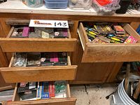 Top view of three open wooden drawers filled with boxes and loose screws, staples, and fasteners.
