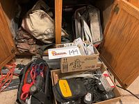 Overview of assorted tool bags and boxes with tools and electrical supplies on a wooden garage floor.