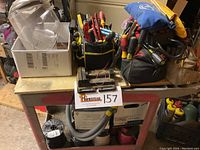 Two black and yellow soft tool bags filled with a variety of hand tools like screwdrivers, pliers, files, and cutters on a metal rolling cart.