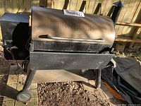 Side view of entire grill with wheels and lower shelf