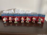 Seven dwarf figurines front view with original boxes and styrofoam inserts behind