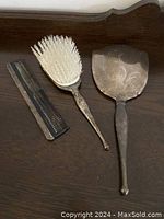 Top view of hand mirror, hairbrush and comb on wooden surface
