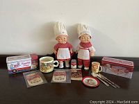 Front view showing all items including two Campbell's Soup kids dolls, advertising tins, mugs, utensils, small plate, and advertising cards.
