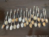 Top view of all 18 silver plated character spoons lined up on a wooden surface showing the varying character handles.