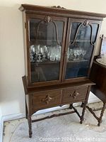 Front angled view of the solid wood china cabinet showing glass doors with shelves inside and drawers below.