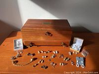 Full lot overview including wooden jewelry box, earring pairs laid out on table, and jewelry cases with some earrings inside.