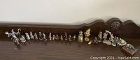 Full length view of all metal character miniatures on a wooden ledge, arranged in a line, varying in size and type.