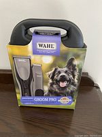 Front view of Wahl Groom Pro pet grooming clippers set in original box and carrying case showing branding, product image and happy dog picture.