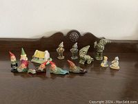 Wide view showing the full collection of pixies and gnomes in various poses with the cottage and seated human figures arranged in front of wooden background