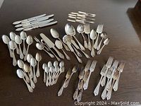 Full view of all flatware pieces arranged on a dark wooden table, showing knives, forks, spoons and specialty utensils.
