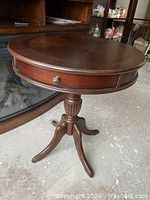 Full view of the mahogany round drum table with drawer showing the top and side profile.