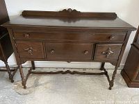 Front view of antique wooden sideboard showing drawers, cupboard doors, and legs.