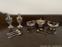 Overview of two shakers, three bowls and spoons on wood surface
